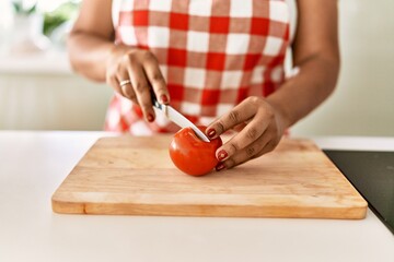 Hispanic brunette woman cooking cutting tomatoes at the kitchen