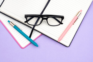 Open notebooks, diaries, reading glasses and pens as a concept for reading, accounting and planning the working day, household spending, retirement savings