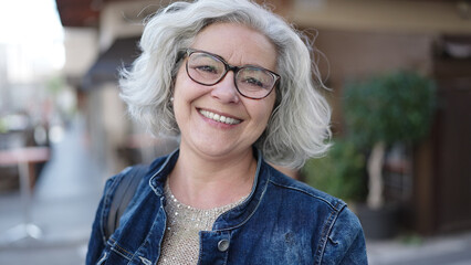 Middle age woman with grey hair smiling confident at street