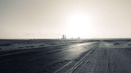silhouette of the cement factory in the middle of the desert and the smoke rising high and stretching long away from it
