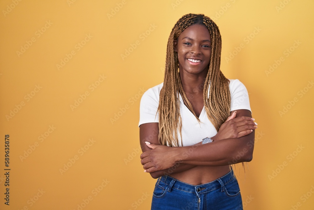 Canvas Prints African american woman with braided hair standing over yellow background happy face smiling with crossed arms looking at the camera. positive person.