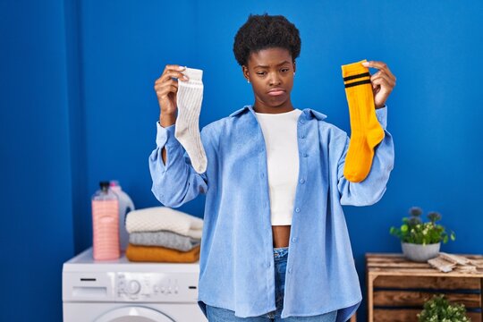 African american woman holding clean andy dirty socks depressed and worry for distress, crying angry and afraid. sad expression.