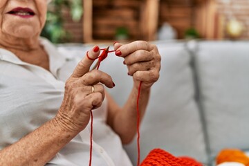 Senior grey-haired woman smiling confident sewing using lane and needle at home