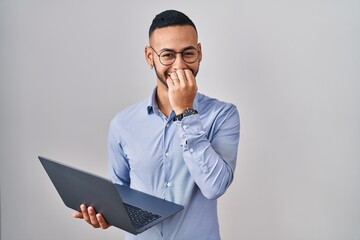 Young hispanic man working using computer laptop laughing and embarrassed giggle covering mouth...