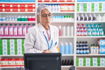 Middle age woman with tattoos working at pharmacy drugstore with hand on stomach because indigestion, painful illness feeling unwell. ache concept.