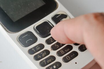 fingers or hands of someone who is holding an old GSM mobile phone on the keypad