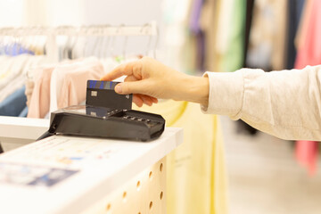A woman holds a credit card in her hand and guides her through the terminal. Pay by credit card, terminal for payment by non-cash method.
