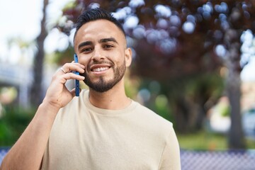 Young hispanic man smiling confident talking on the smartphone at park