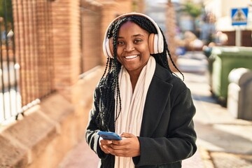 African american woman smiling confident listening to music at street