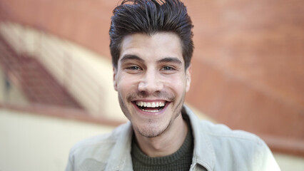 Obraz premium Young hispanic man smiling confident standing at street