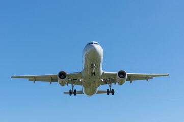 Modern passenger jet shown approaching for landing shown against a blue sky.