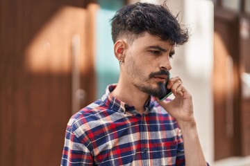 Young hispanic man talking on the smartphone at street