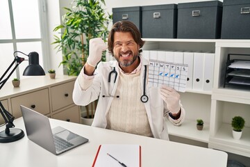 Fototapeta premium Handsome middle age doctor man holding holidays calendar annoyed and frustrated shouting with anger, yelling crazy with anger and hand raised