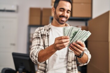 Young hispanic man ecommerce business worker counting dollars at office
