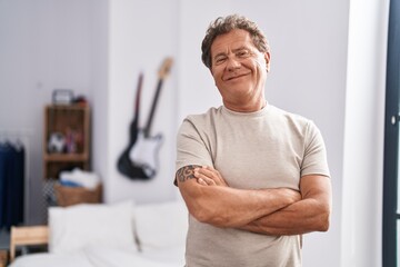 Middle age man smiling confident standing with arms crossed gesture at bedroom