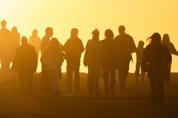 Silhouettes of people in yellow light of a bright orange sunset