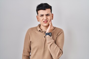 Non binary person standing over isolated background touching mouth with hand with painful expression because of toothache or dental illness on teeth. dentist