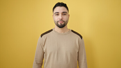 Young arab man standing with relaxed expression over isolated yellow background