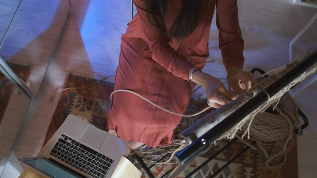 top view woman weaves macrame by video tutorials