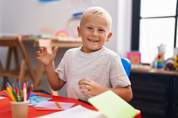 Little caucasian boy painting at the school celebrating achievement with happy smile and winner expression with raised hand