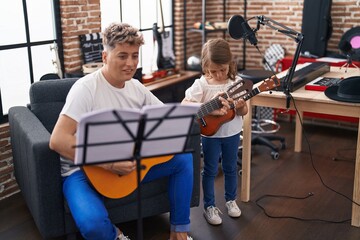 Father and daughter playing classical guitar and ukulele at music studio