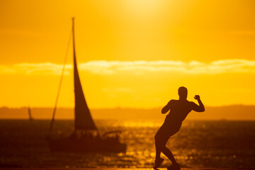 An inspired man dancing on the waterfront at sunset