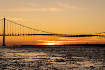 Fototapeta na wymiar Suspension bridge over the sea at sunset