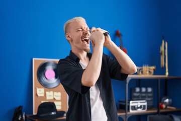 Young caucasian man artist singing song at music studio