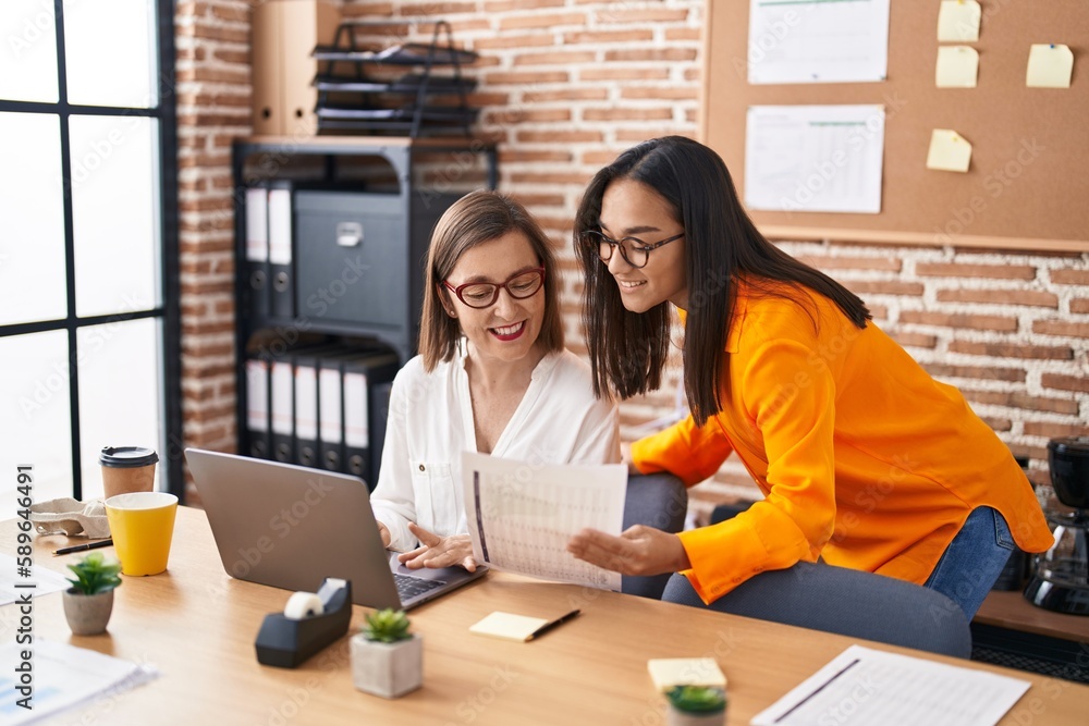 Canvas Prints two women business workers using laptop reading document at office