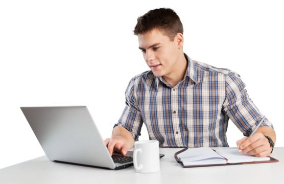 Happy young man works on his laptop with coffee at the table