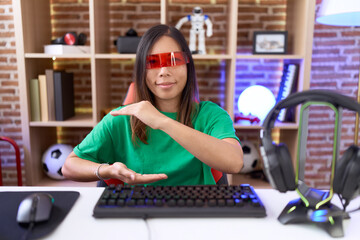 Fototapeta na wymiar Middle age chinese woman wearing virtual reality glasses gesturing with hands showing big and large size sign, measure symbol. smiling looking at the camera. measuring concept.