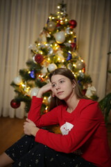 beautiful girl at home in pajamas sitting near the Christmas tree. red Christmas pajamas. the girl lit a sparkler near the Christmas tree. the magic of Christmas new year at home