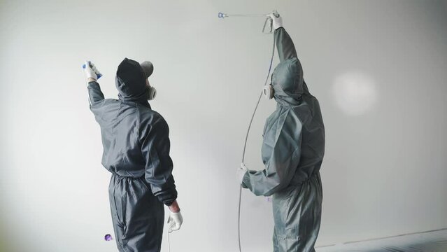 Workers paint a wall with white airless paint. Airless spray painting. Home renovation.