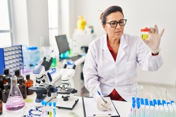 Middle age hispanic woman wearing scientist uniform analysing urine test at laboratory © Krakenimages.com