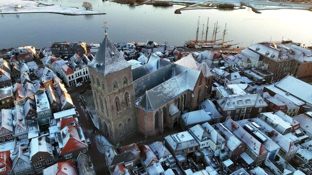 Kampen city view with the Buitenkerk chruch at the river IJssel during a cold winter sunrise at the start of a cold bright winter day with light snow on the roofs. 
