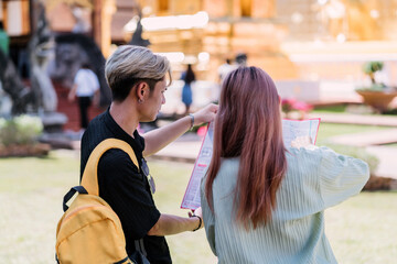 confused tourist lover lost looking map sheet. young asian couple wondering about location at asia temple become frustrated unfolding paper. asian lover unfolding map finding way to travel after lost