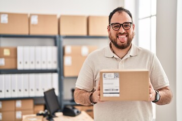 Fototapeta na wymiar Plus size hispanic man with beard working at small business ecommerce sticking tongue out happy with funny expression.