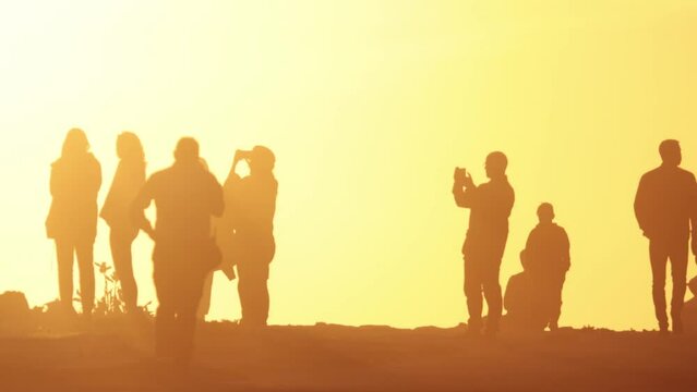 Silhouettes of people in the light of sunset - people taking photo on setting sun