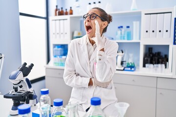 Young woman working at scientist laboratory clueless and confused with open arms, no idea and doubtful face.
