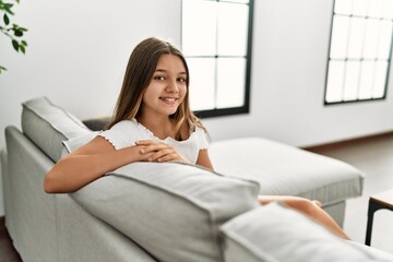 Adorable girl smiling confident sitting on sofa at home