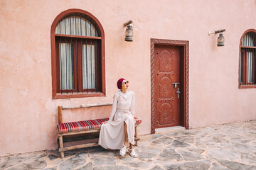 Happy asian girl in headscarf walking at old town or heritage village in UAE