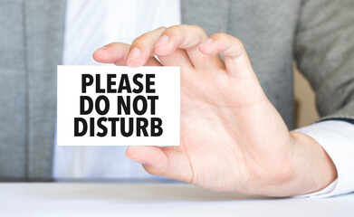 man's hand holding paper sheet with please do not disturb words