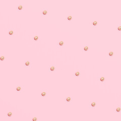 Shinny pearl beads, creative pattern, pastel pink background.