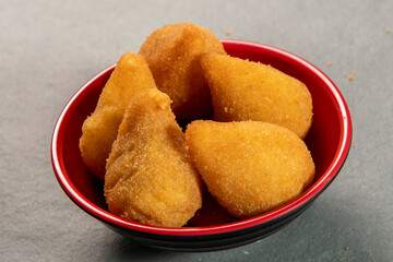 traditional fried coxinha in plate on slate background, popular brazilian snack