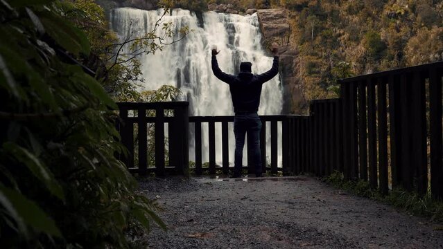 Young man at Marokopa Falls while opening his arms. Waikato, New Zealand