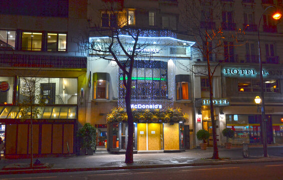 Paris, France - December 9th 2018 : The McDonalds of the Grands Boulevards, decorated for Christmas. The entry and the windows are covered by wood panels, because the yellow jackets broken it.