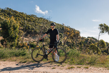 Fototapeta premium Young male with bicycle relaxing during training enjoying the view