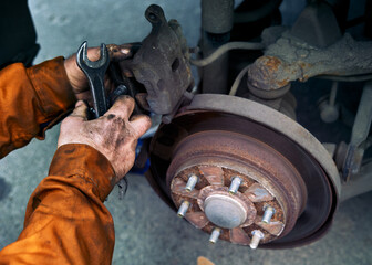Car rusty brake rotor in automobile warckshop photo with mechanick hands and tools