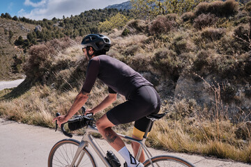 Male cyclist is conquering the challenging uphill terrain on his gravel bike.Sportsman training...
