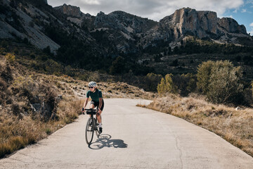 Woman cyclist riding a gravel bike with a view of the spanish mountains.Fit athlete wearing...